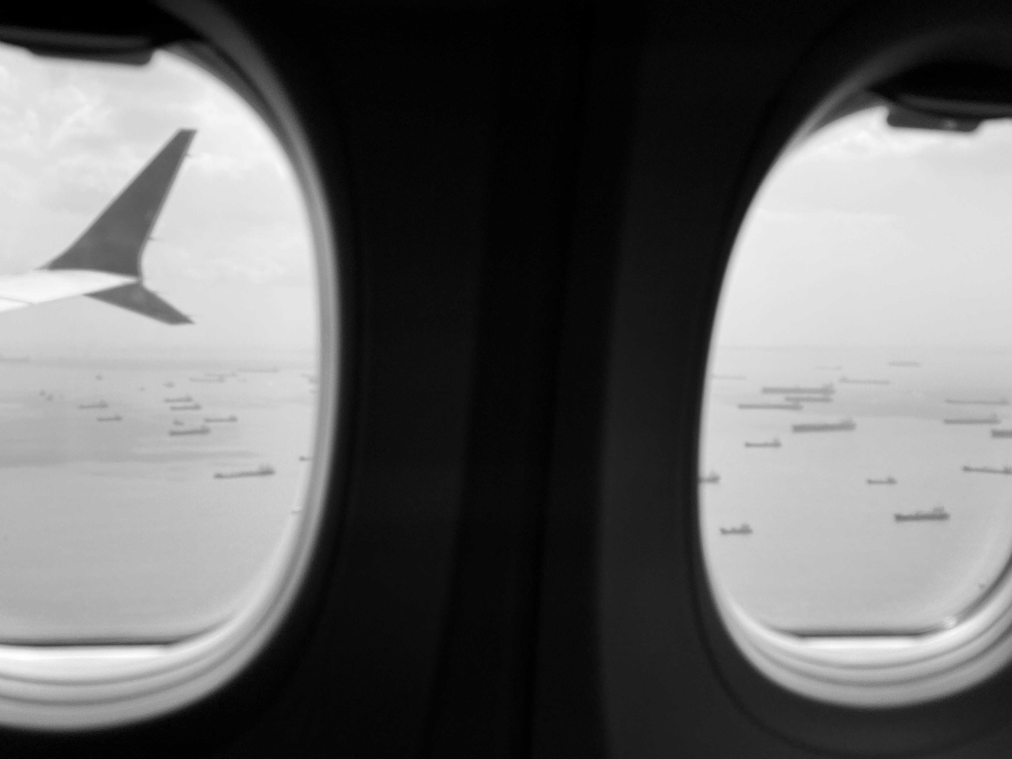 View from airplane windows of clouds and distant land.